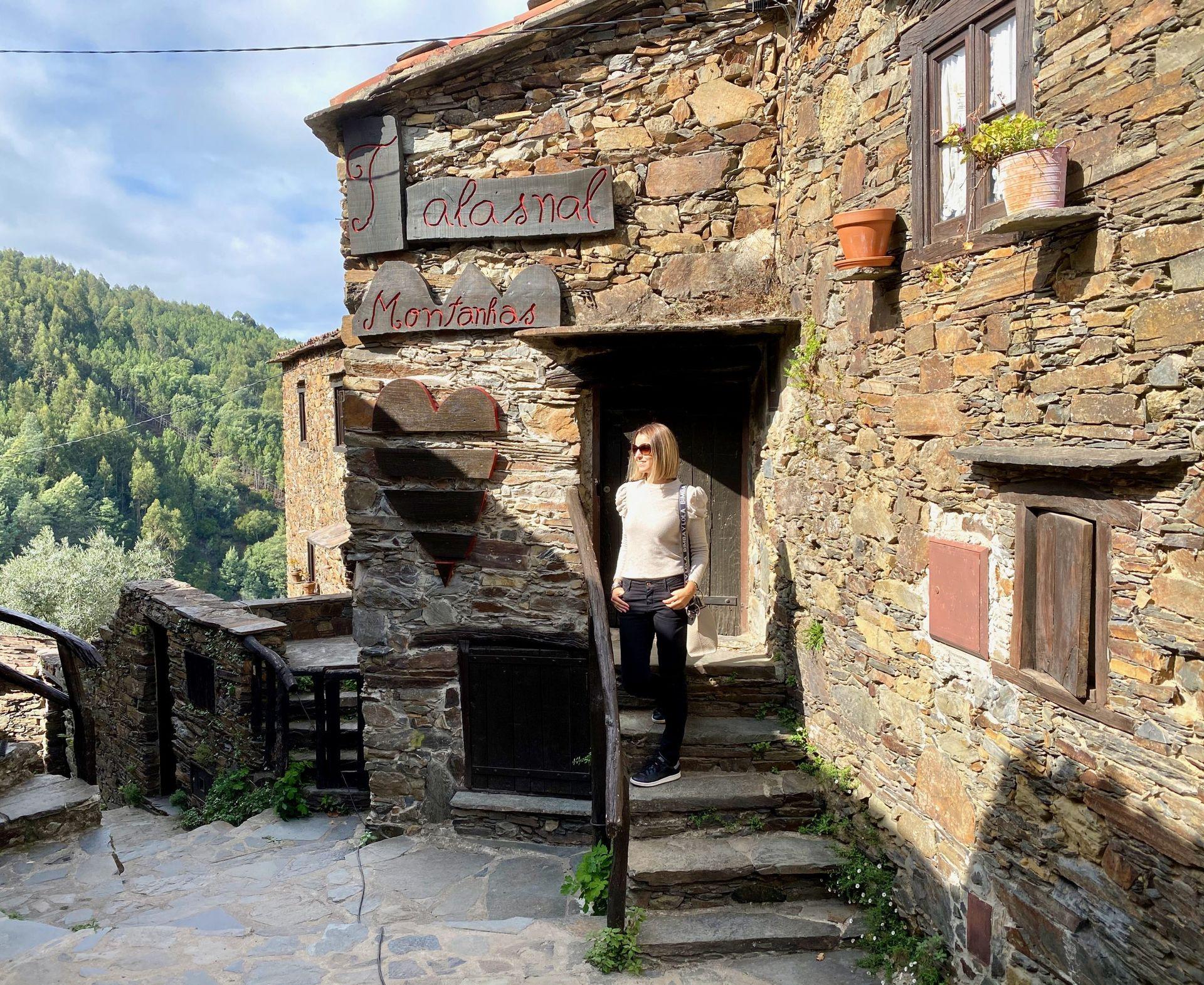 Person standing at the entrance of a rustic stone building with signs and heart decorations.